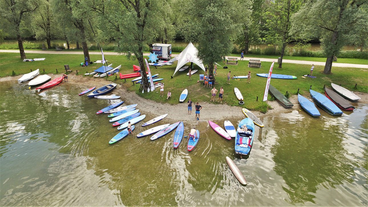 a group of people standing around a body of water with surfboards