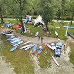 a group of people standing around a body of water with surfboards